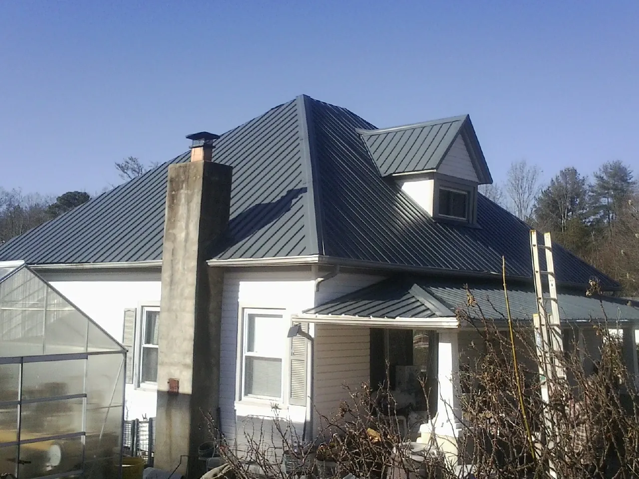 Dark blue standing seam metal roof on a white farmhouse with dormer — Slate & Tile Roof Repair by Roofing Brothers in Ripley